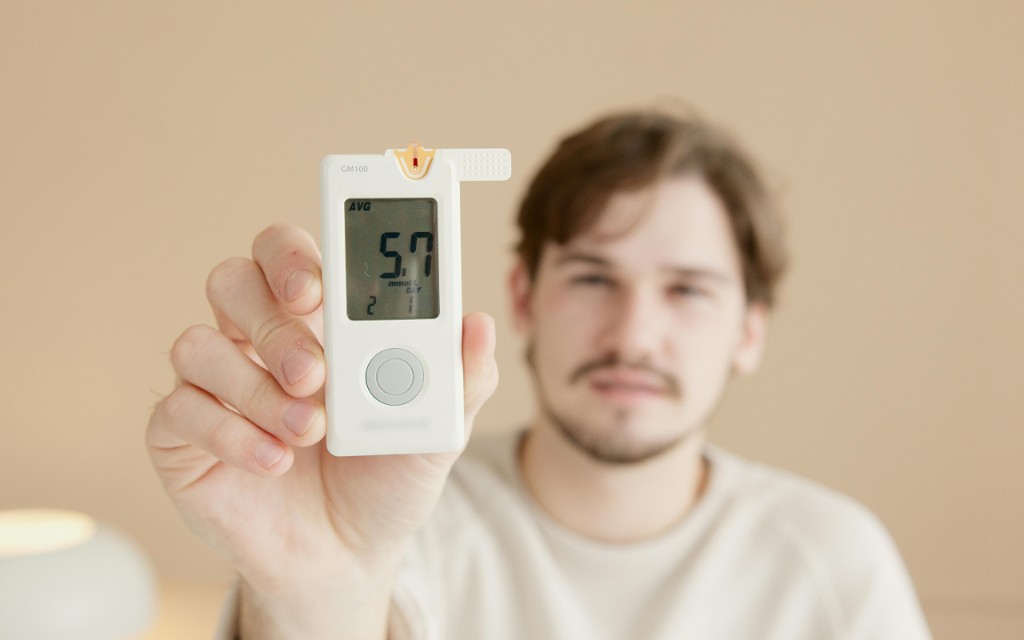 Person holding a blood glucose meter with a digital reading, test strip inserted